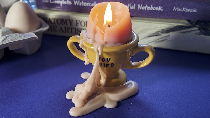 photo of an egg candle lit and melted on a yellow egg dish that says "you tried" in handwriting, dish by adamjk