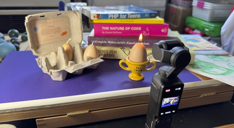 photo of my desk showing a video being made of an egg candle from Scandles burning on an adamjk "you tried" egg dish