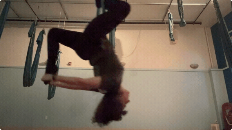 animated gif of me on aerial silks in a swinging inversion, switching which leg i hold onto behind me