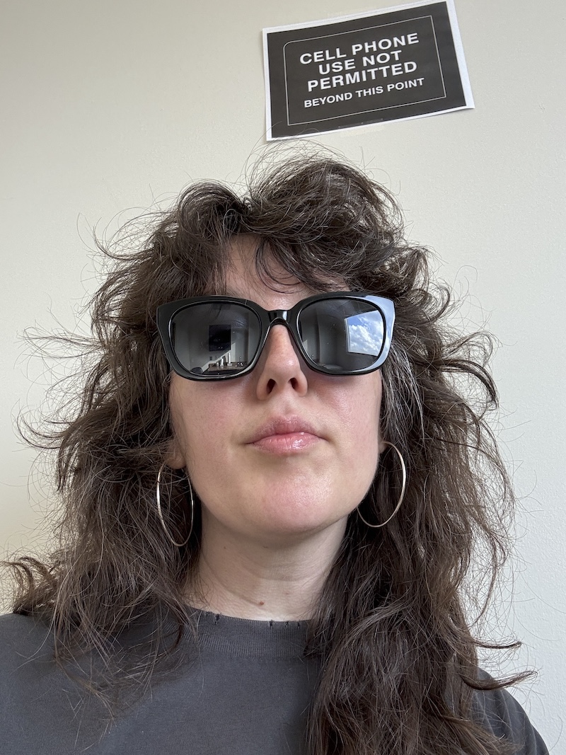 selfie of me at the diagnostics place to get bloodwork. i'm sitting under a sign that says "cell phone use not permitted beyond this point"