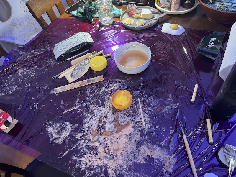 photo of a messy air dry clay session on my table near some cheese and crackers