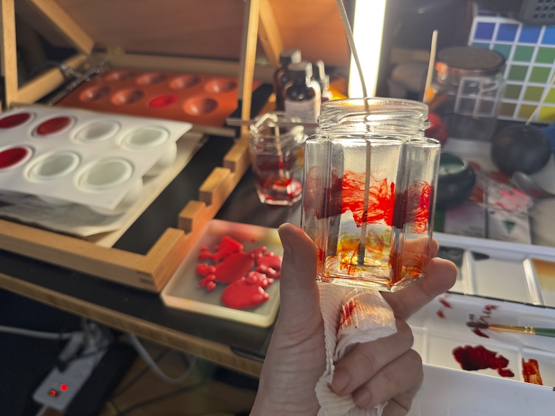 photo of me holding up an empty candle jar that i painted red and yellow dye into the inside of