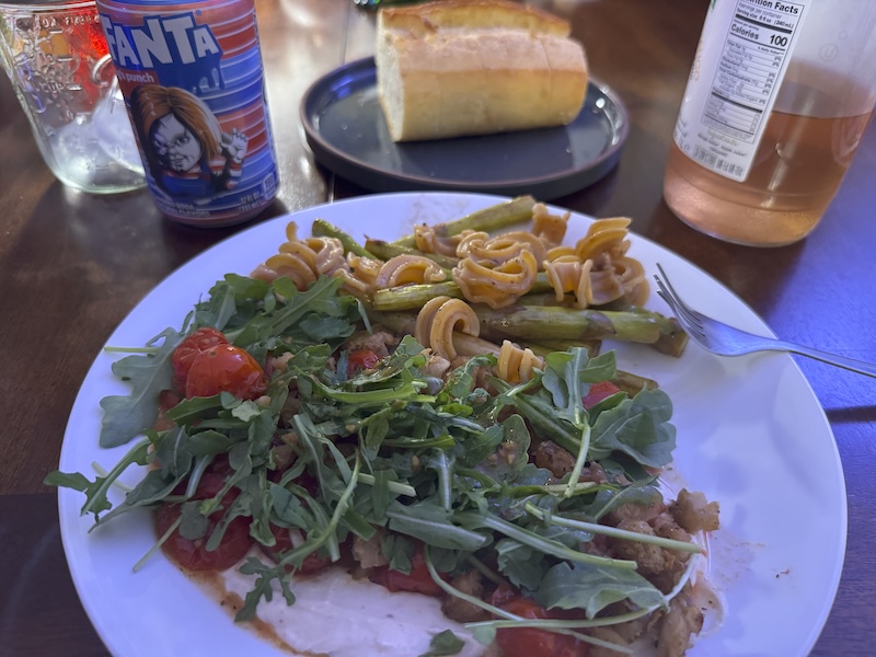 photo of dinner one night: arugula on tomatoes, beans and a yogurt tahini sauce with pasta and asparagus. we're drinking chucky fanta fruit punch soda hehehe