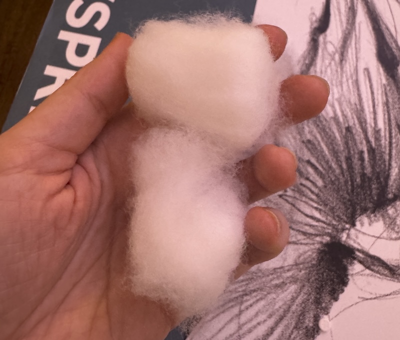 photo of my hand holding two large marshmallow-shaped piles of cotton