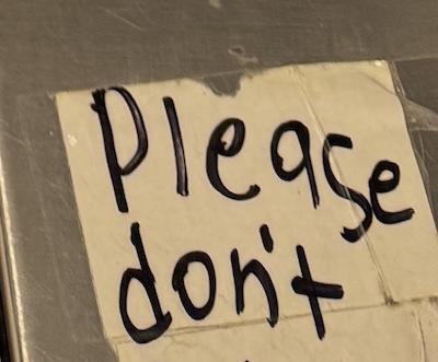 the previous photo of the cvs self-checkout cropped to the lower right corner where there's a paper that says "Please don't"