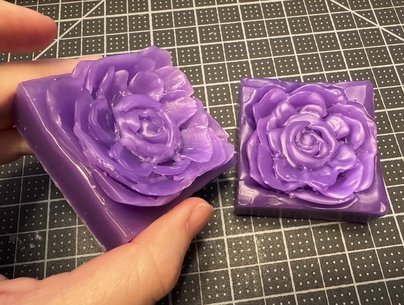 two purple beeswax blocks i carved flowers into, i'm holding one of them closer