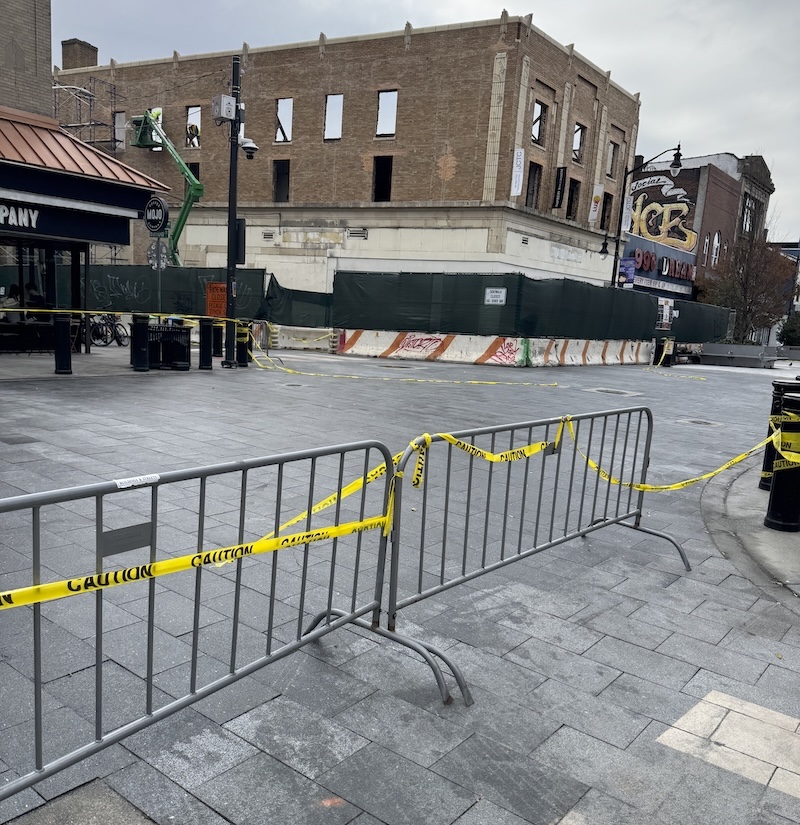 photo of the pedestrian plaza with newly power-washed gray concrete brick floors, in the background is a building partially torn down