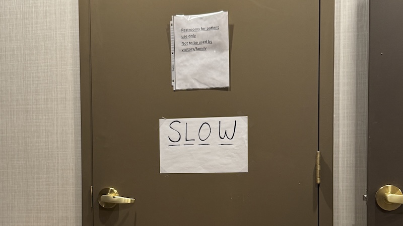 bathroom door of my dad's nursing room that has a paper on it that says "SLOW" with each letter underlined. above is a sign telling visitors/family that the bathroom is only for patients.