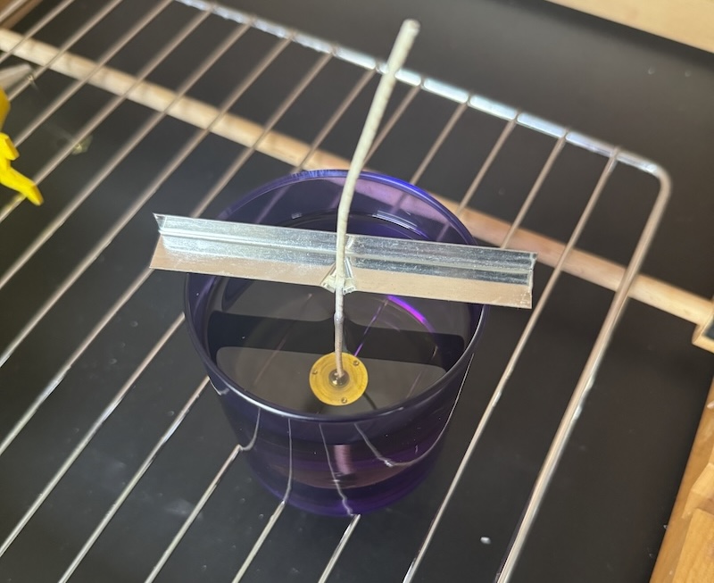 photo of a candle curing in a periwinkle glass on a cooling rack