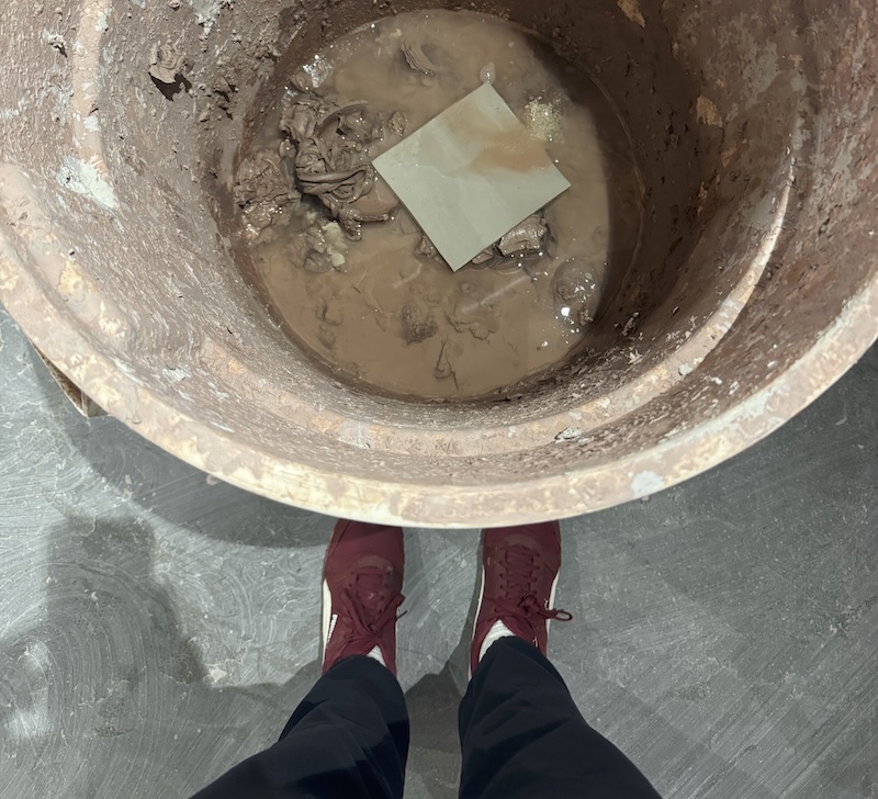 photo from my pov looking down at a large bin filled with recycled clay, including a white clay slab i just tossed in