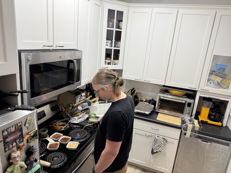 photo of phil in my kitchen making creme brulee and he's got a propane tank that's hidden behind him but you can see the torch in his hand