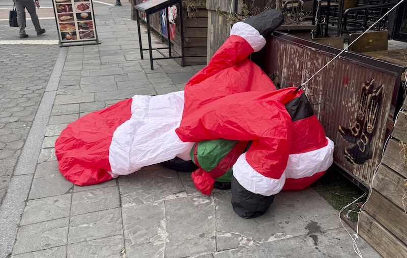 photo of a mostly-deflated santa decoration outside of a bar during broad daylight