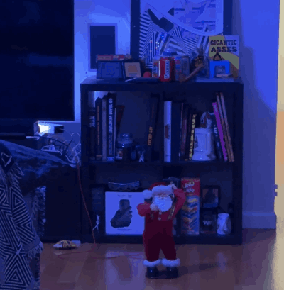 animated gif of my small animatronic white santa toy shaking his hips on the floor of our dark living room