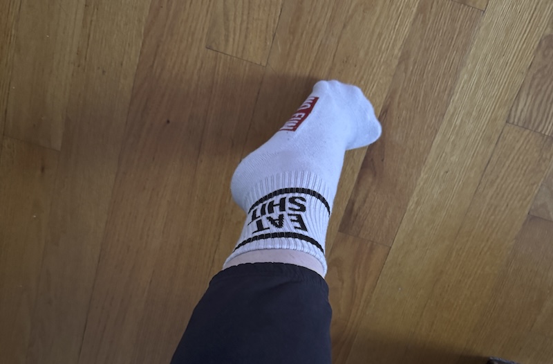 photo of my foot wearing a sock that says 'eat shit'