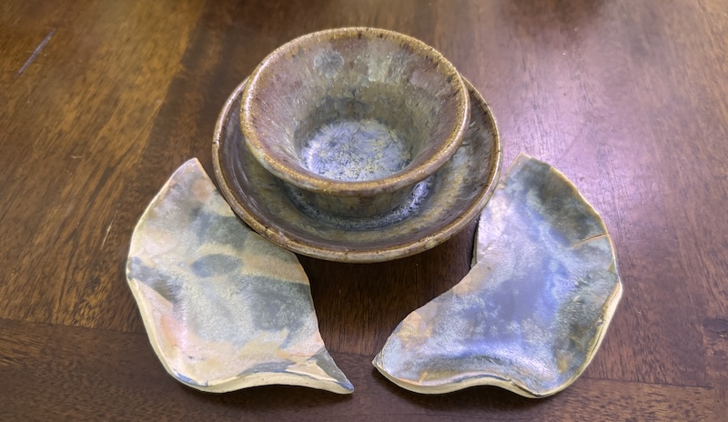 photo of crystal glazed pieces including two broken halfs of a small dish and a small cup inside a saucer with blue crystals pooling at the bottom