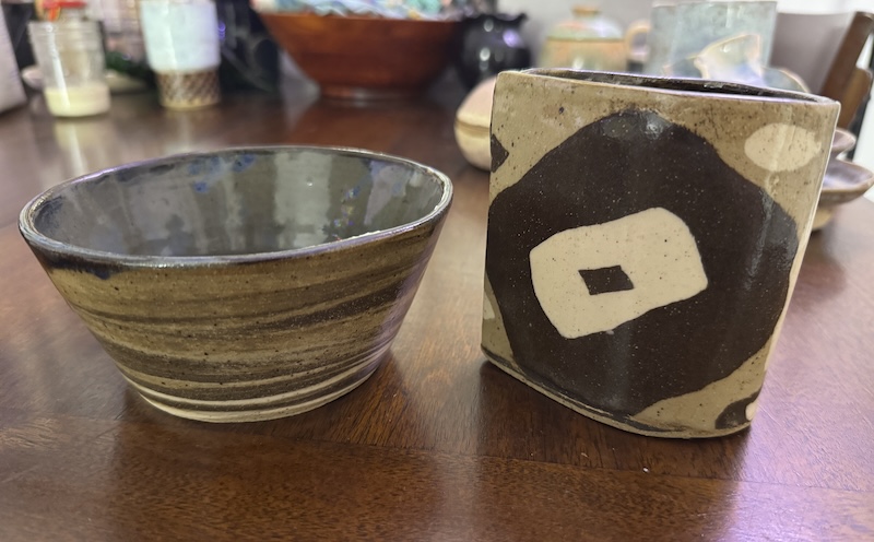 photo of a multi-clay-color thrown bowl with a gray and blue inside, next to a hand-made tear-drop shaped cup in a nerikomi style of different colors of clay squares rolled onto it