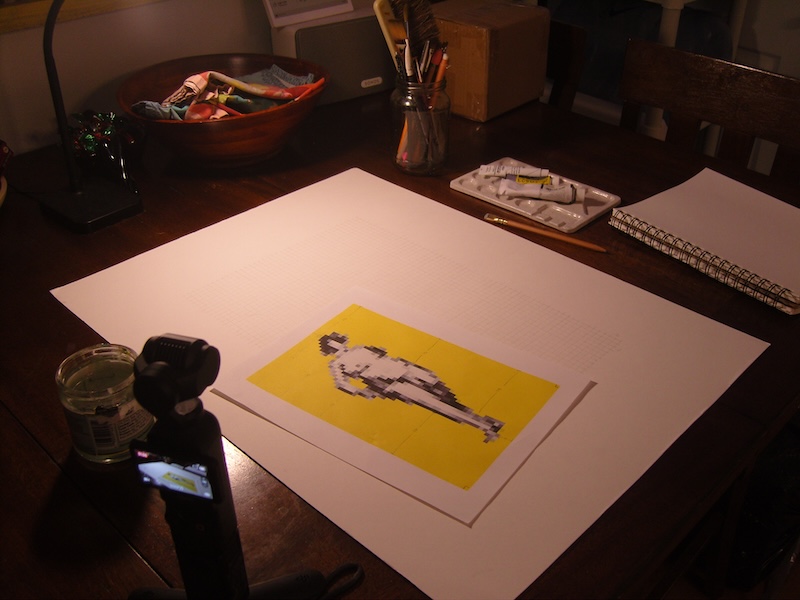 photo of the painting paper with a grid drawn on it and you see the digital reference of a grayscale pixel art figure of a woman with a yellow background. you also see the camera recording the process.