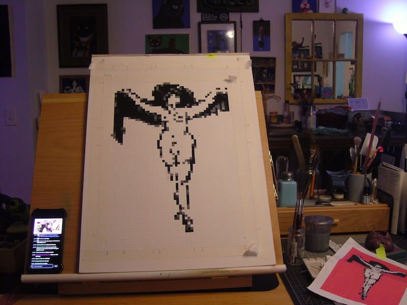 photo the grayscale figure of the above nude woman in a hat and scarf painted on paper on my easel. next to it is the print out of the digital reference, showing the background will be a medium "cosmos" pink.