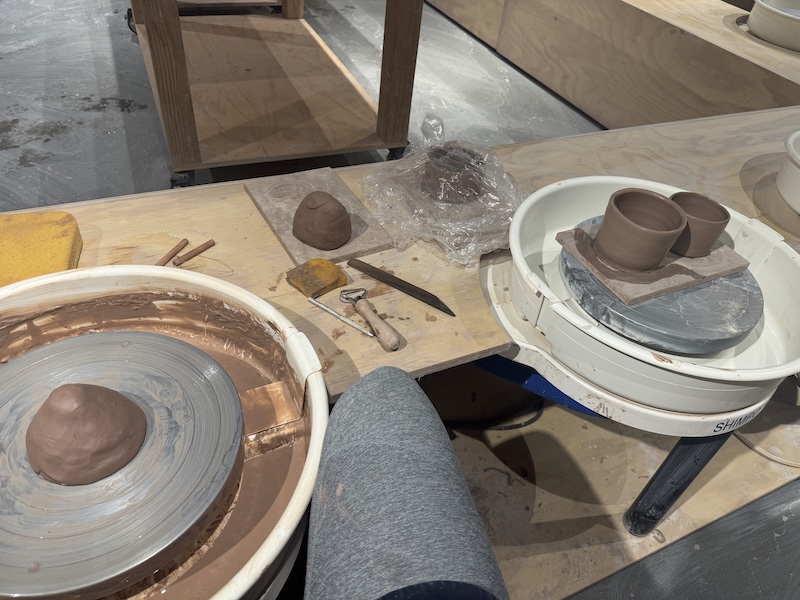 photo of my ceramic wheel throwing setup at the studio. i have two cups to the side i just threw and a mound on the wheel about to be worked on