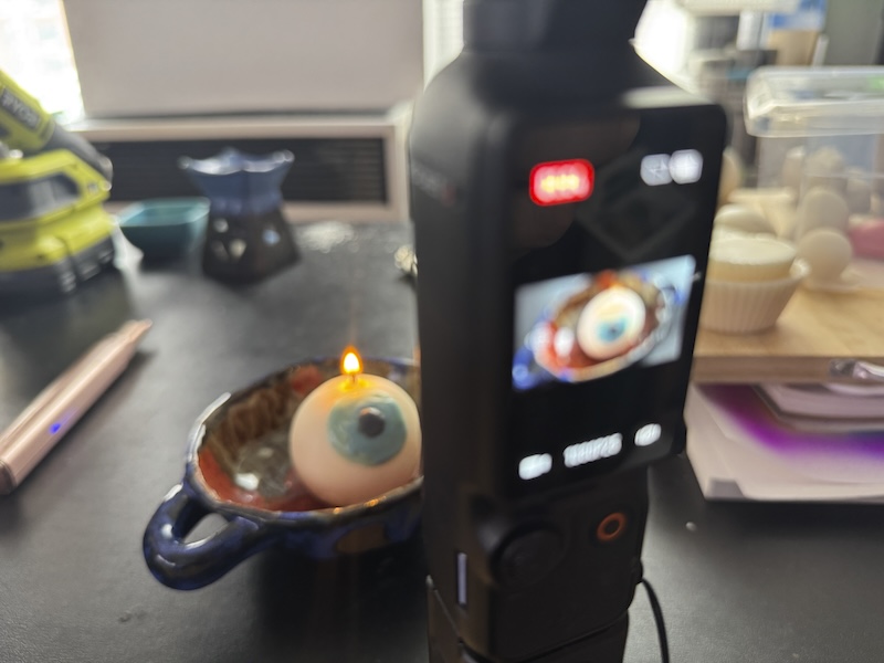 photo of my camera recording a wick test of a spherical white candle that i painted a blue eye on