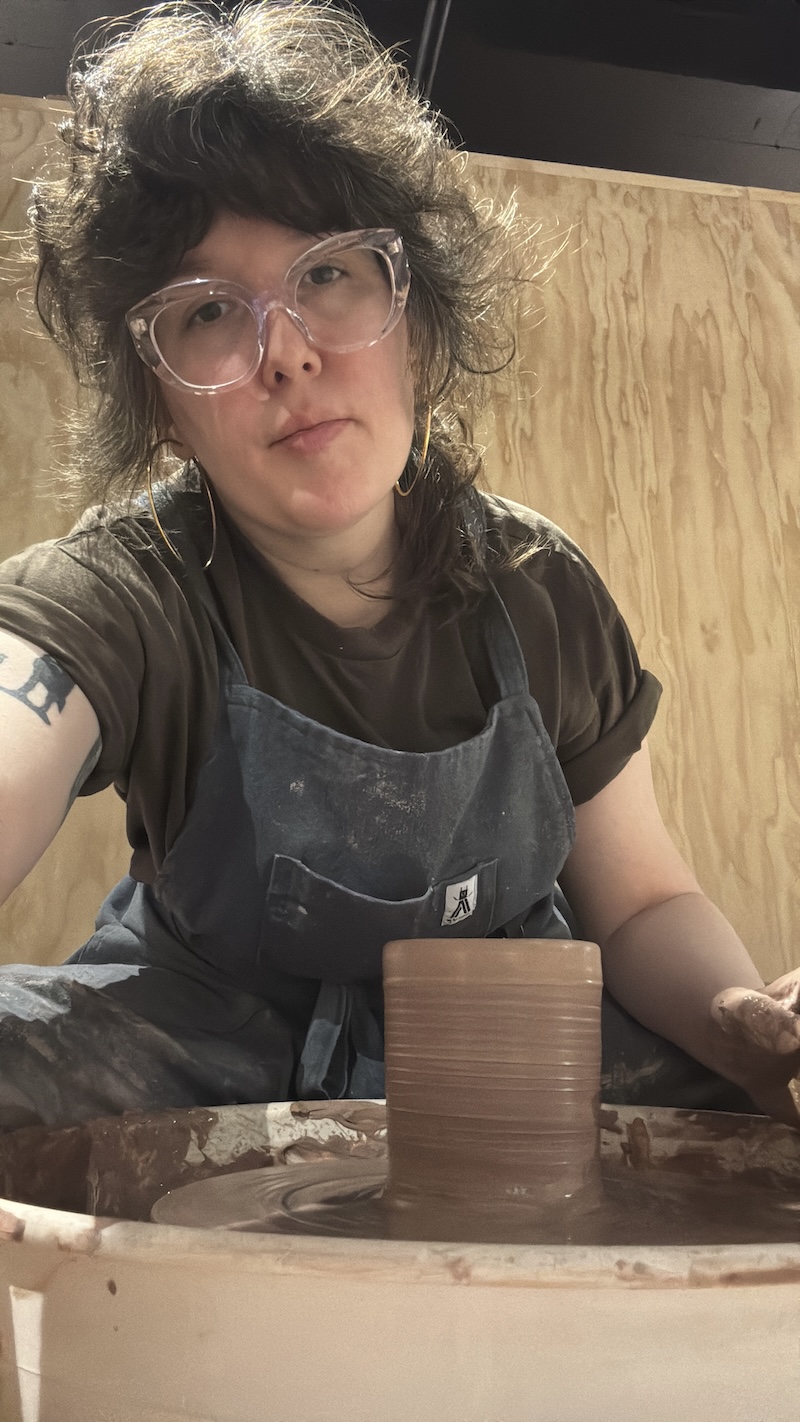 photo of me posing cutely at the ceramics wheel with a cylinder i just pulled