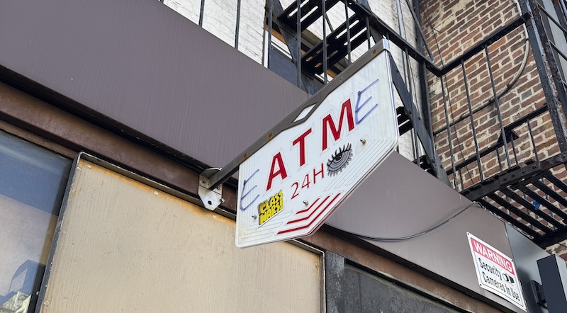 sign above a public atm in the city that was grafittied to now say "EATME"