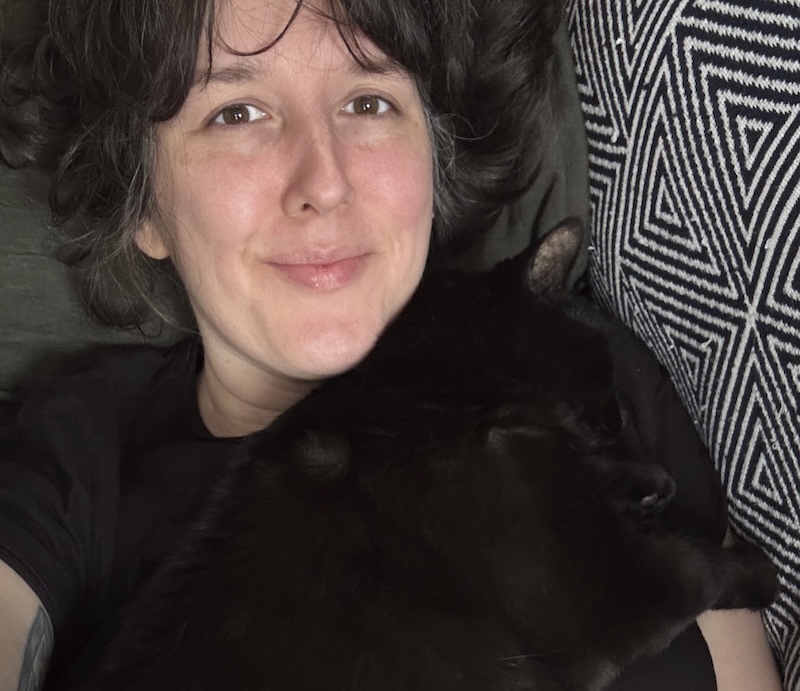 photo of my black cat pumagreg sleeping and cuddling on my chest as we lay on the couch this morning