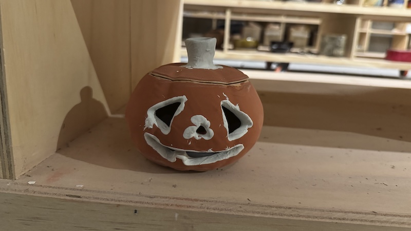 a photo of a pre-glaze-fire jack o'lantern of mine sitting on the shelf