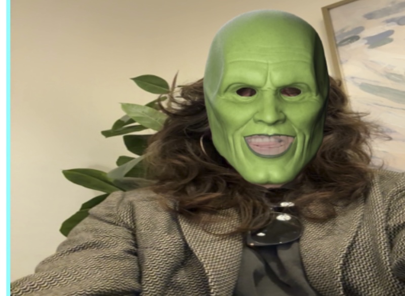 a webcam photo of me in a blazer in an office lobby and there's a layer over the image of the green mask from the film The Mask over where my face is