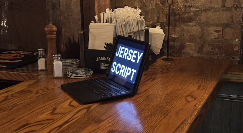photo of a bar and on top is a laptop open with a screen saying "JERSEYSCRIPT"