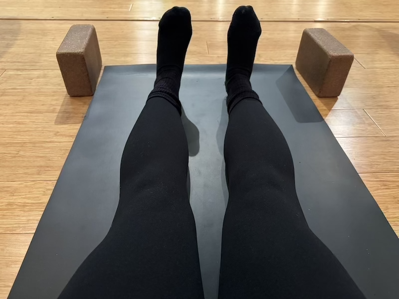 yoga studio photo of my legs on the mat with two yoga blocks up front. one of my socks has a little hole on the toe and you can kinda see how muscular my legs are lol