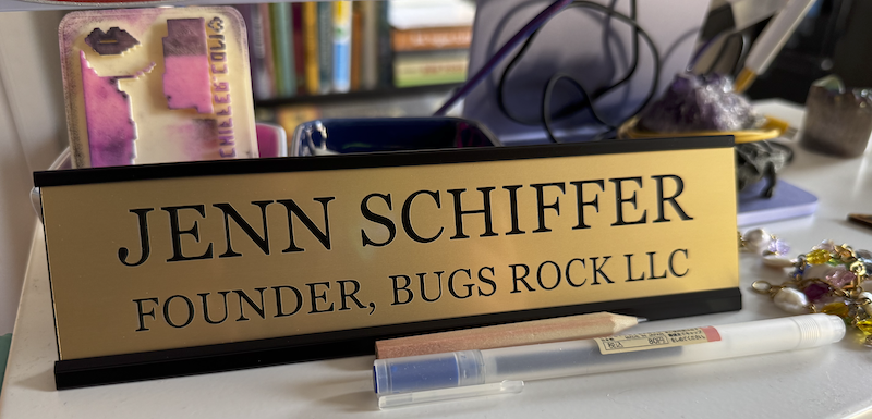 a desk placard that says "jenn schiffer founder, bugs rock llc"