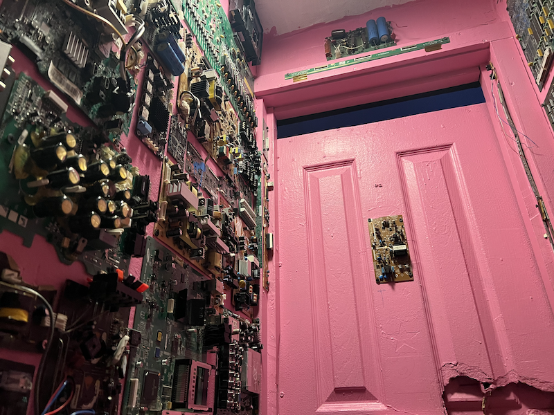photo from the toilet at wonderville where the walls are pink and covered in montherboards and circuit boards